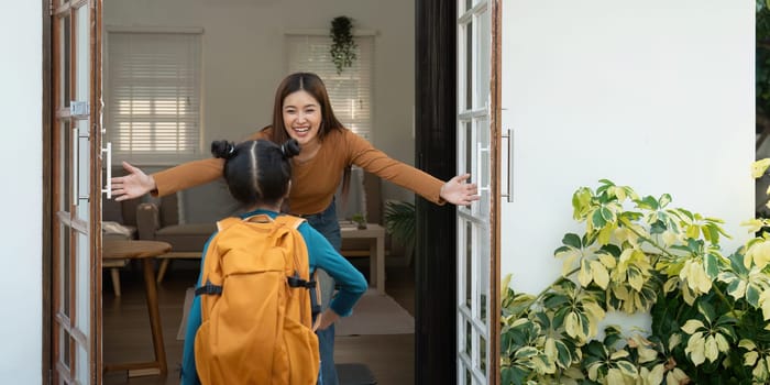 A loving mother greets her daughter with open arms as she prepares to leave for school, encapsulating a moment of love and excitement.