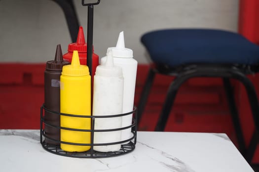 Various condiment bottles sit together on a table at a dining area.