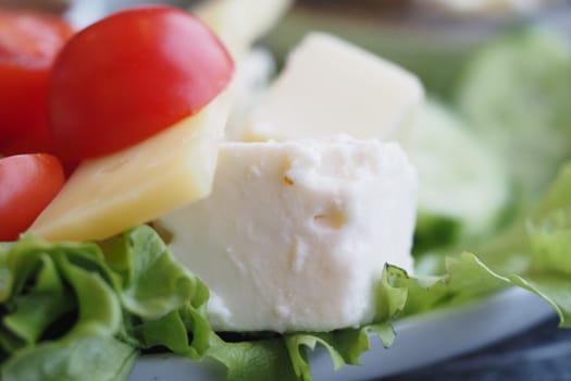 A fresh salad with lettuce, tomatoes, feta, and pineapple.
