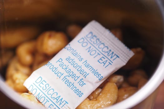 Cashew nuts are stored in a container with a desiccant packet for freshness.