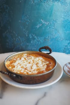 Traditional turkish menemen served in rustic pottery on a marble table.