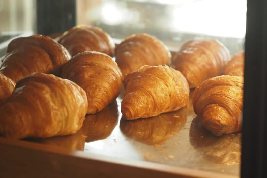 Warm, golden croissants are neatly arranged in a bakery display case.