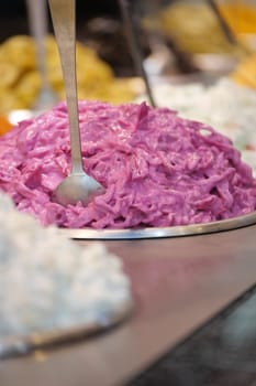 A vibrant display of purple cabbage salad is ready for customers.