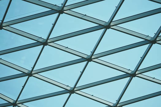 A geometric glass ceiling showcases a blue sky above, highlighting design.