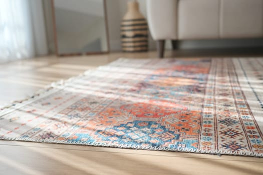 Brightly designed rug lies on a wooden floor beside a couch.