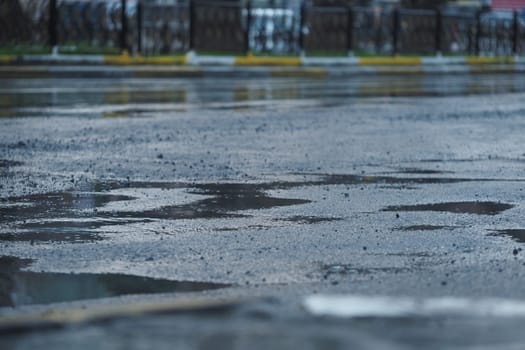Puddles collect on a city street pavement after a rainy day.