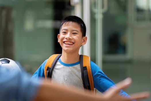 A cheerful young boy is happily welcomed by his mother after a day at school, creating a warm and loving atmosphere at the school entrance.