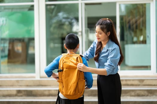 A caring mother helps her young son adjust his backpack, ensuring he is ready for the school day. The moment captures the essence of support and love in a nurturing environment.