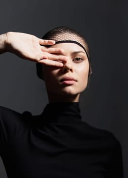 Stylish female model showcasing a unique pose and expression, set against a dark background. Emphasizes modern fashion and artistic portraiture.