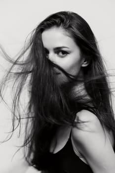 Striking portrait of a confident young woman with long hair in motion, showcasing beauty and elegance. Ideal for fashion and lifestyle imagery.
