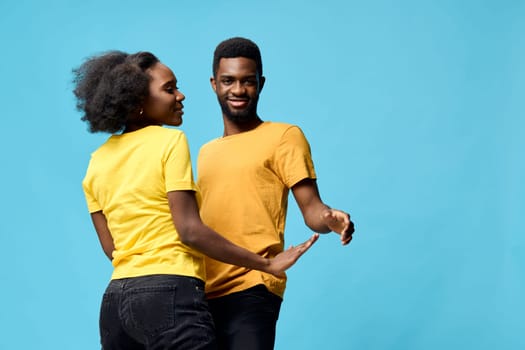 A vibrant, joyful scene of a young couple dancing together, wearing yellow t shirts, set against a bright blue background, capturing emotions of happiness, connection, and love, perfect for lifestyle