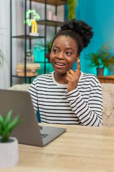 African American woman responding to emails on laptop. Sitting on sofa, taking short breaks, feeling relaxed and satisfied with work. Home atmosphere, productive indoor workspace, positive mood