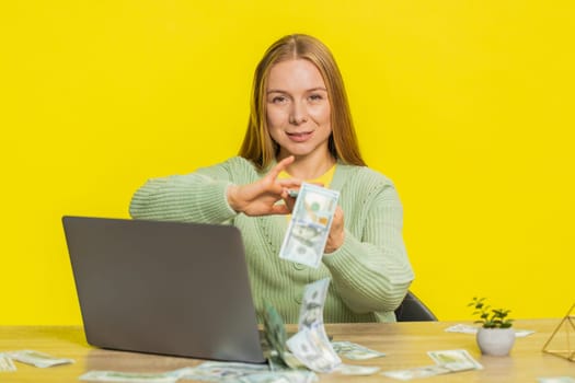Caucasian rich woman wasting throwing sharing money dollar cash around more tips big profit winning lottery casino jackpot, successful shopping payment purchase cashback. Girl on yellow background.