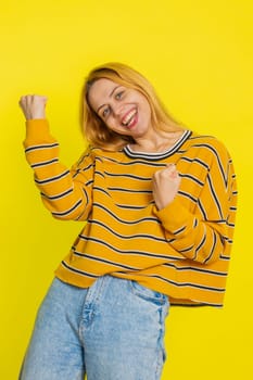 Happy joyful Caucasian woman celebrating success victory, winning birthday, lottery jackpot goal achievement play game good positive news triumph. Young adult girl isolated on yellow studio background