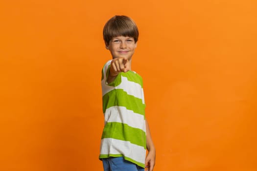 Happy preteen child boy kid laughing out loud after hearing ridiculous anecdote reaction on funny joke feeling carefree amused. Positive people. Little children isolated on studio orange background