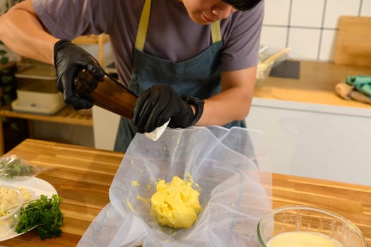 Close up of man seasoning freshly made butter with pepper in the kitchen.