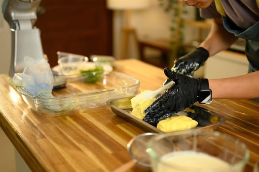 Close up of man shaping fresh homemade butter on tray in a modern kitchen.