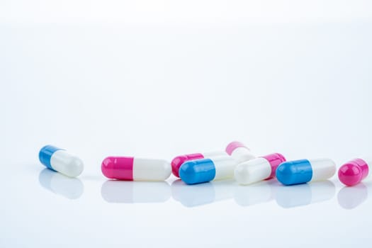 Blue and pink capsule pills spread on white background, showcasing pharmaceutical products, healthcare concepts, and the role of prescription medicine in advancing treatment and patient well-being.