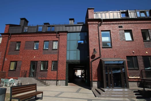 A sturdy brick building stands tall with a set of stairs leading up to its entrance and a bench conveniently located in front of it, inviting passersby to rest