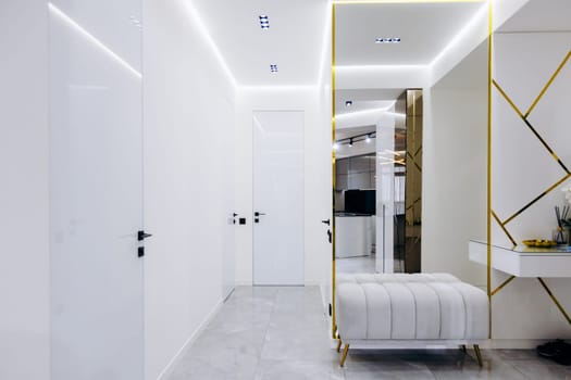 A long hallway featuring a wooden bench elegantly placed against the wall, adorned with a stylish mirror hung on the wall surface