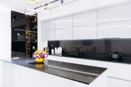 On the countertop in the kitchen, there is a beautiful vase filled with a stunning arrangement of fresh flowers that adds charm