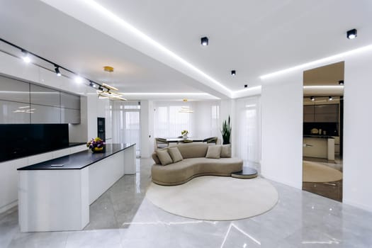 The scene features a cozy living room that includes a comfortable couch and, in the background, a wellequipped kitchen area