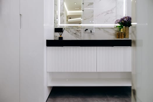 This is a beautifully designed bathroom that features a stylish sink, an elegant mirror, and vibrant flowers adorning the countertop