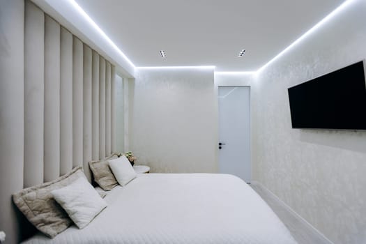 In the cozy bedroom, there is a comfortable bed situated alongside a flat screen television mounted on the wall above it, enhancing the spaces charm