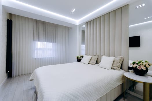 A cozy bedroom featuring a comfortable bed, a stylish nightstand, a decorative mirror, and an entertainment television set