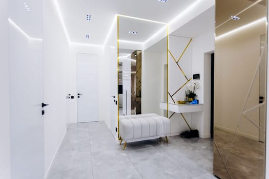 In a hallway, there is a wooden bench and a large mirror mounted on the wall, which enhances the aesthetic appeal of the space