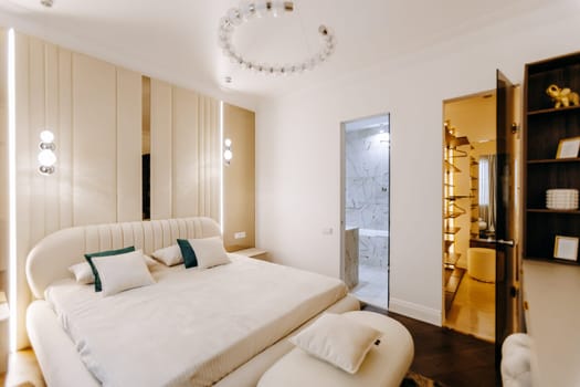 A cozy bedroom featuring a large bed, a stylish ottoman, and an attached bathroom for convenience and comfort, creating a perfect retreat