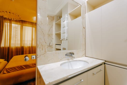 A welldesigned bathroom that includes a sink feature and a spacious, elegantly styled large mirror, enhancing the overall aesthetic appeal
