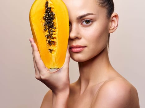 Beautiful young woman with papaya fruit facial mask isolated on white background Skincare and beauty concept