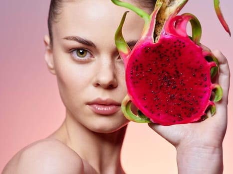 Woman holding exotic dragon fruit in front of face with eyes closed in peaceful moment