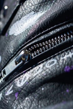 This image captures a detailed close up of a zipper that is prominently featured on a stylish black leather jacket