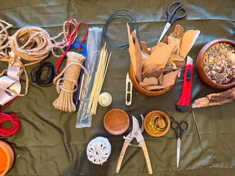 Tools and materials for creating ikebana art arranged on a work surface. Preparation, focus and the meditative process of floral design.