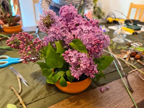 Lilac arrangement in progress on creative workspace. Natural beauty, floral art and mindfulness through ikebana composition.