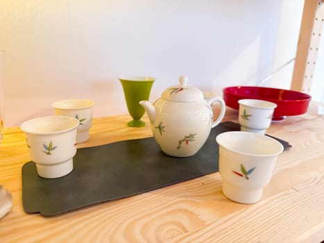 Porcelain teapot and cups arranged on wooden table. Mindfulness, ritual and harmony in the context of traditional tea ceremony.