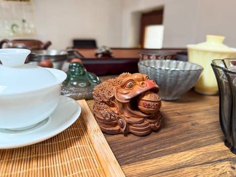 Ceramic toad and tea accessories on wooden tea table during traditional ceremony. Ritual, harmony and cultural symbolism in tea practice.