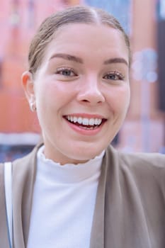 Young Caucasian businesswoman looks at the camera with a radiant smile.She radiates confidence,happiness, and positivity, making her an ideal image for lifestyle, fashion, and personal branding topics
