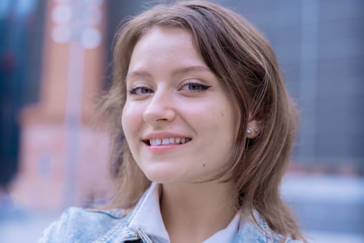 Close-up of a Caucasian woman with a serious expression looking directly at the camera. The blurred urban background highlights her confident presence and emotional strength in the city.