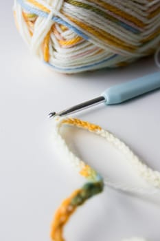 Colorful yarn and crochet hook on white surface.