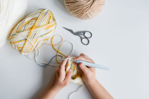 Child crocheting with yarn and crochet hook.