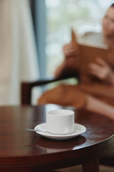 A calm atmosphere showcasing a white cup on a wooden table, representing relaxation and a cozy reading moment, ideal for coffee lovers and tranquil settings