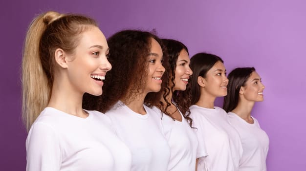 Group Of Five Smiling Diverse Women Standing In A Row Line Posing On Purple Studio Background, Looking Aside. Female Beauty Diversity, Friendship And Unity Concept. Selective Focus, Panorama