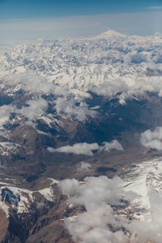 landscape on snowy mountains with clouds from the window of an airplane