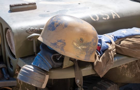 A helmet and gas mask are on a vehicle that says USA. The helmet is old and has a worn look to it