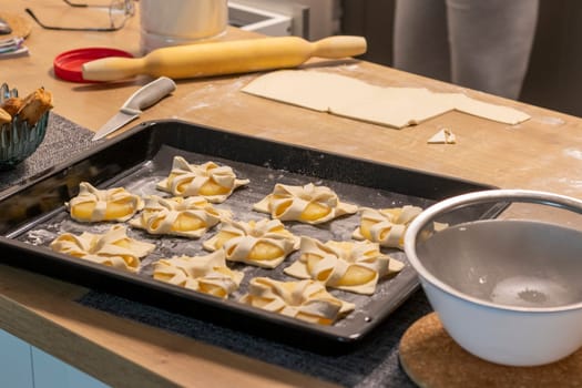 Shot of the a pineapple wedges wrapped in puff pastry on the baking tray on the kitchen counter