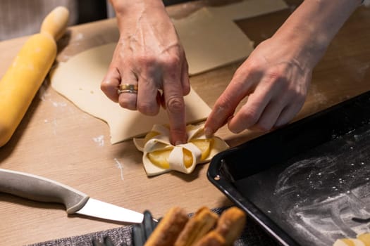 A woman wraps a pineapple wedge in puff pastry