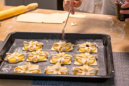 A woman place cherry on the top of the puff pastry with pineapple wedges wrapped.